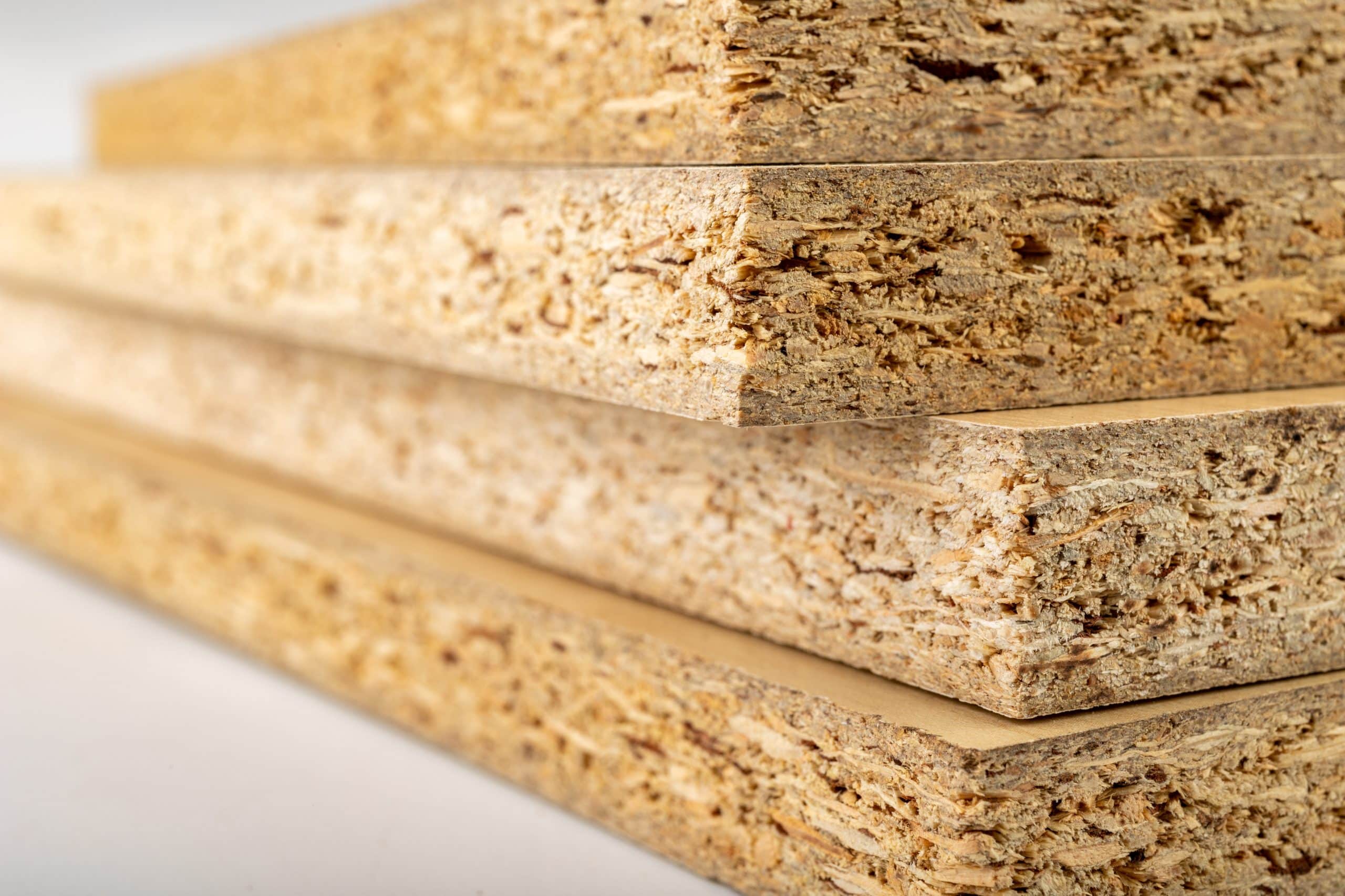 Particleboard with veneer is cut into small pieces. Materials for carpenters to build furniture. Light background.